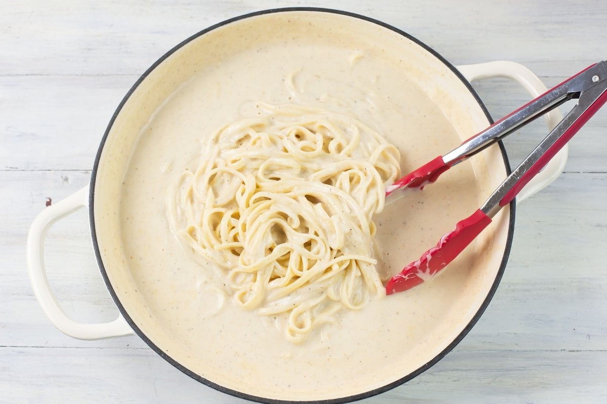 Add linguine pasta to a skillet of homemade spicy alfredo sauce.