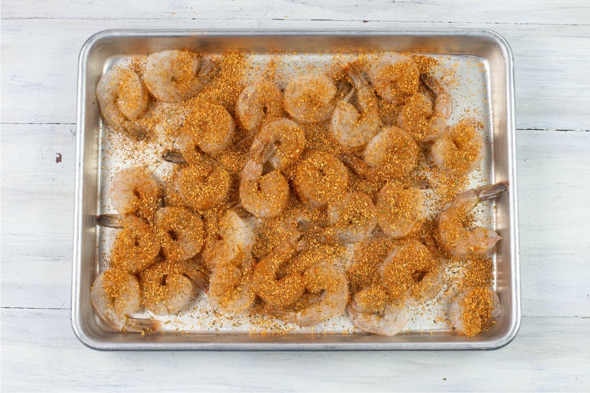 Seasoned raw shrimp on a baking sheet.