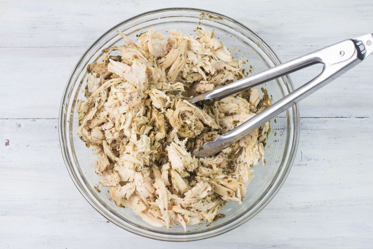 Shredded chicken flavored with pesto in a bowl.
