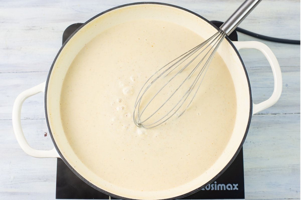 Simmer and thickening spicy alfredo sauce in a skillet.