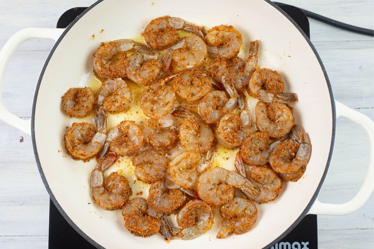 Seasoned shrimp arranged in a single layer in a skillet.