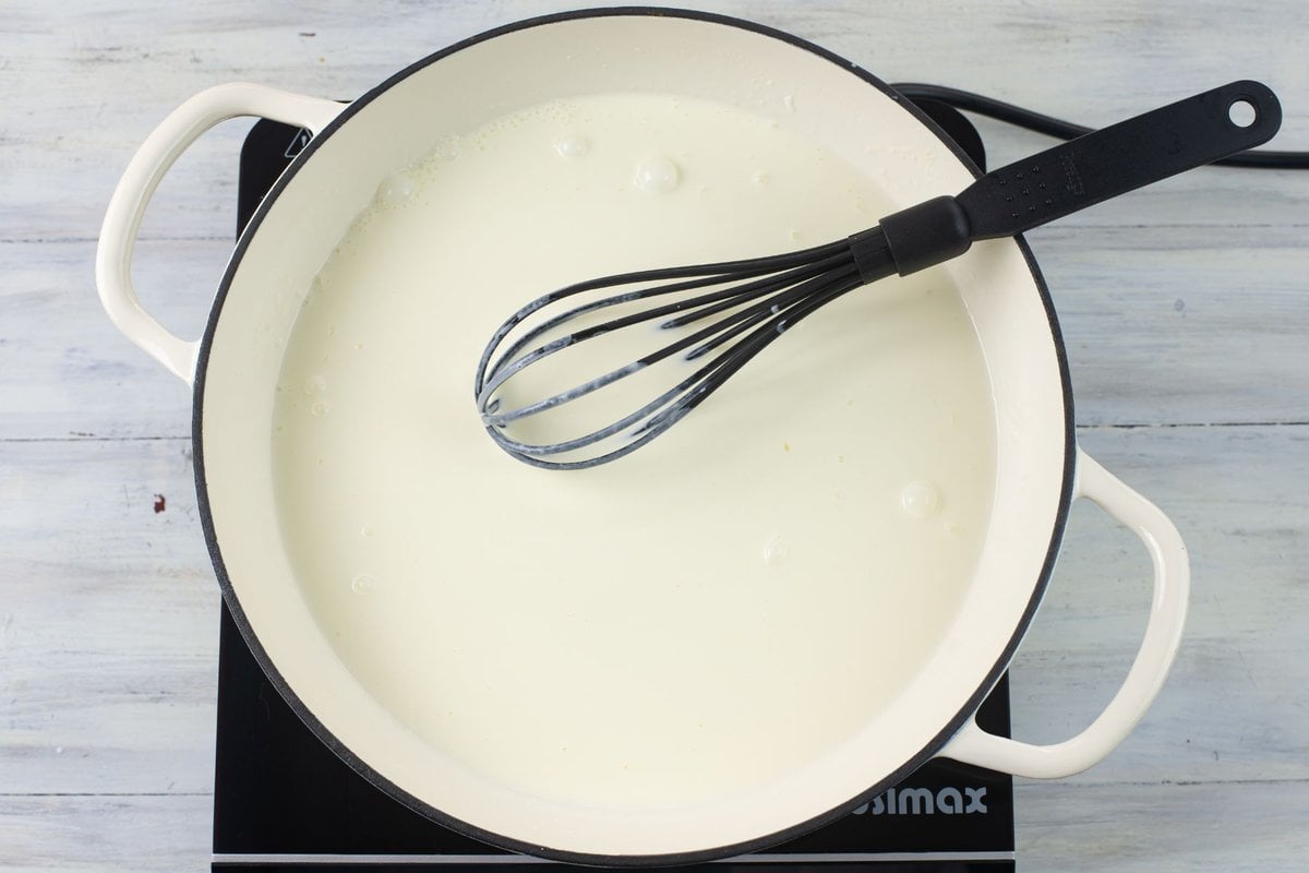 Combining heavy cream with a flour roux in a large skillet.