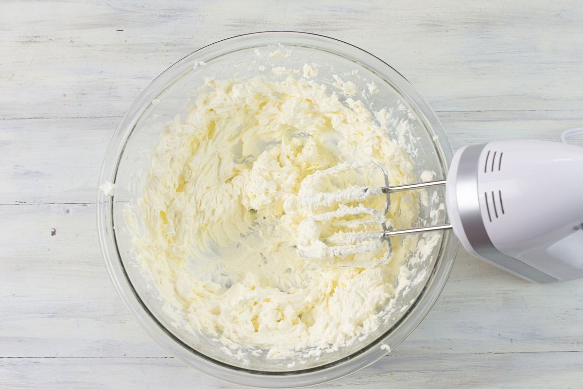 A large bowl of cream cheese that has been beaten with a mixer.