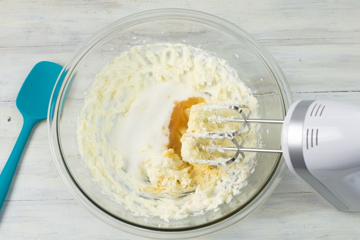 Beating sugar, vanilla and softened cream cheese together in a bowl.