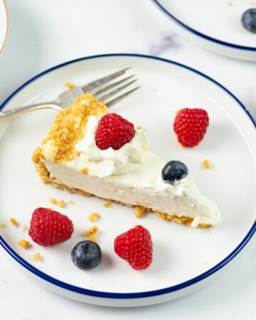 A slice of homemade cheesecake with whipped cream and berries.