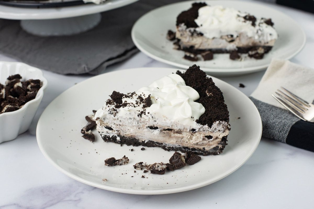 OREO cheesecake slice topped with crushed cookies and served on a dessert plate.