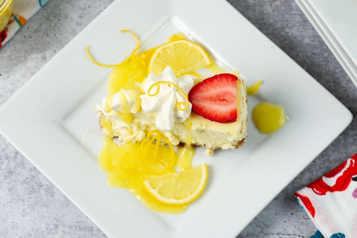 A wedge of strawberry and lemon curd topped cheesecake.