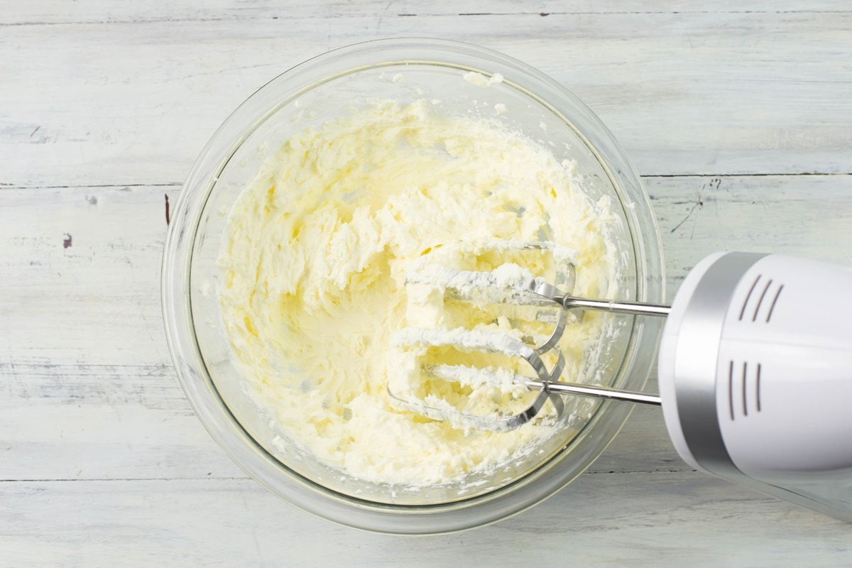 Cream cheese and butter beaten together in a glass mixing bowl.