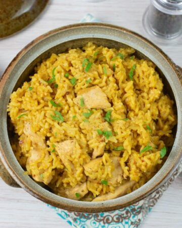 Instant Pot Chicken and yellow rice in a stoneware serving bowl.