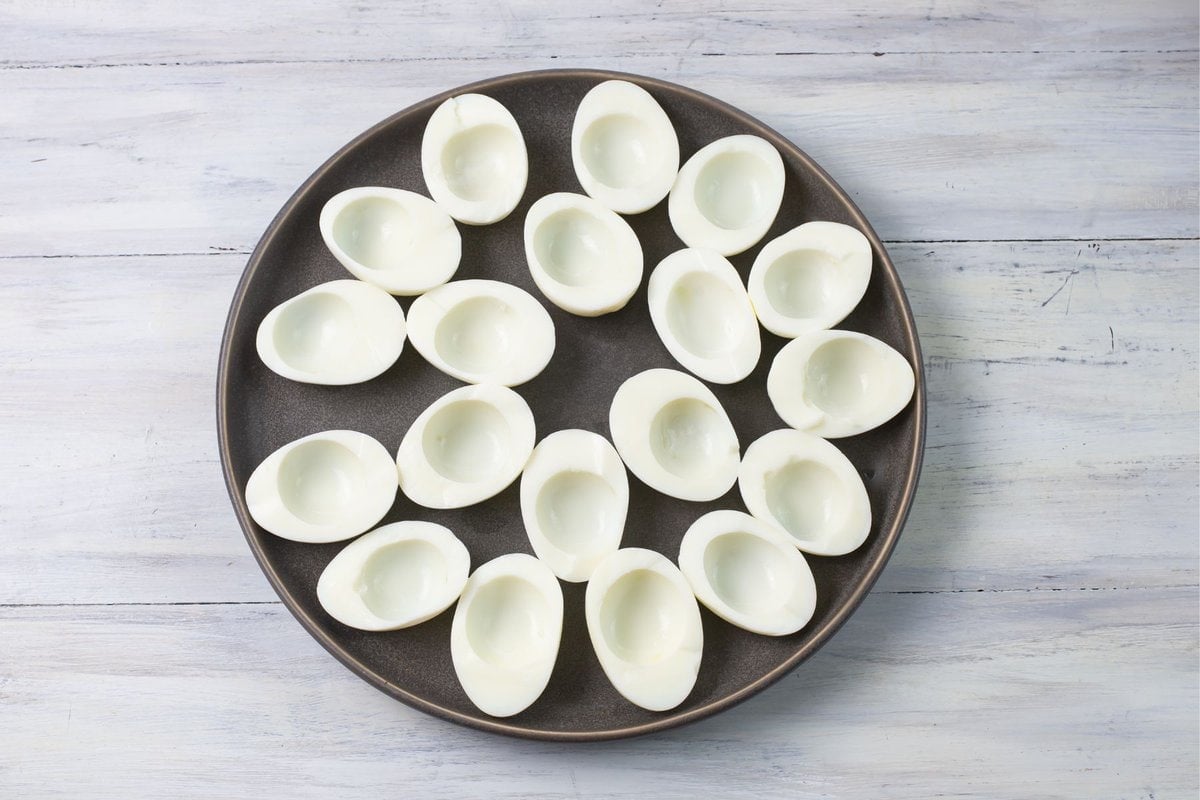 Hard boiled eggs cut in half, yolks removed and arranged on a plate.