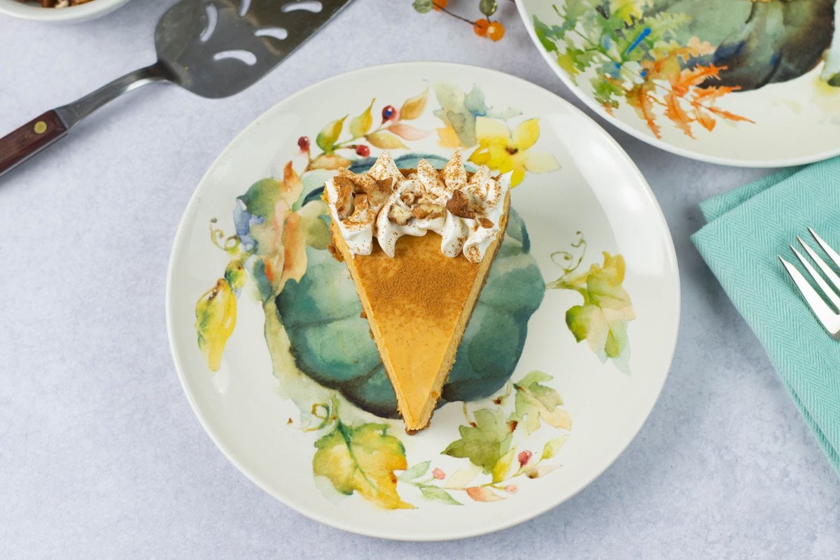 Serving a wedge of pumpkin cheesecake on a plate.