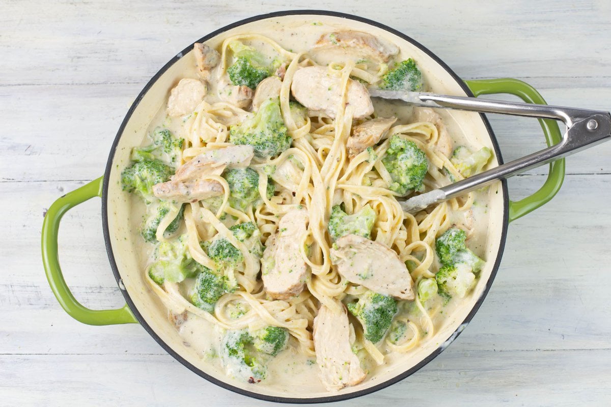 Mixing the cajun chicken slices, broccoli, fettuccine pasta and alfredo sauce before serving.