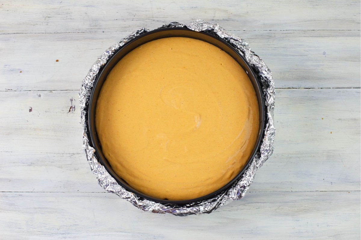 Prebaked pumpkin cheesecake in a pan.