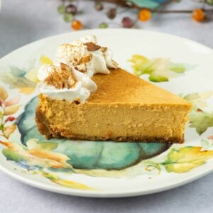 A slice of cheesecake made with pumpkin cheesecake filling on a fall themed dessert plate.