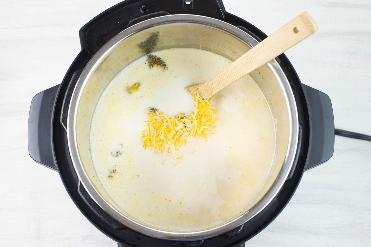 Adding cheese and cream to the broccoli soup.