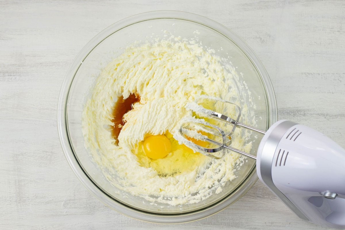 Adding eggs and extracts into creamed butter and sugar.
