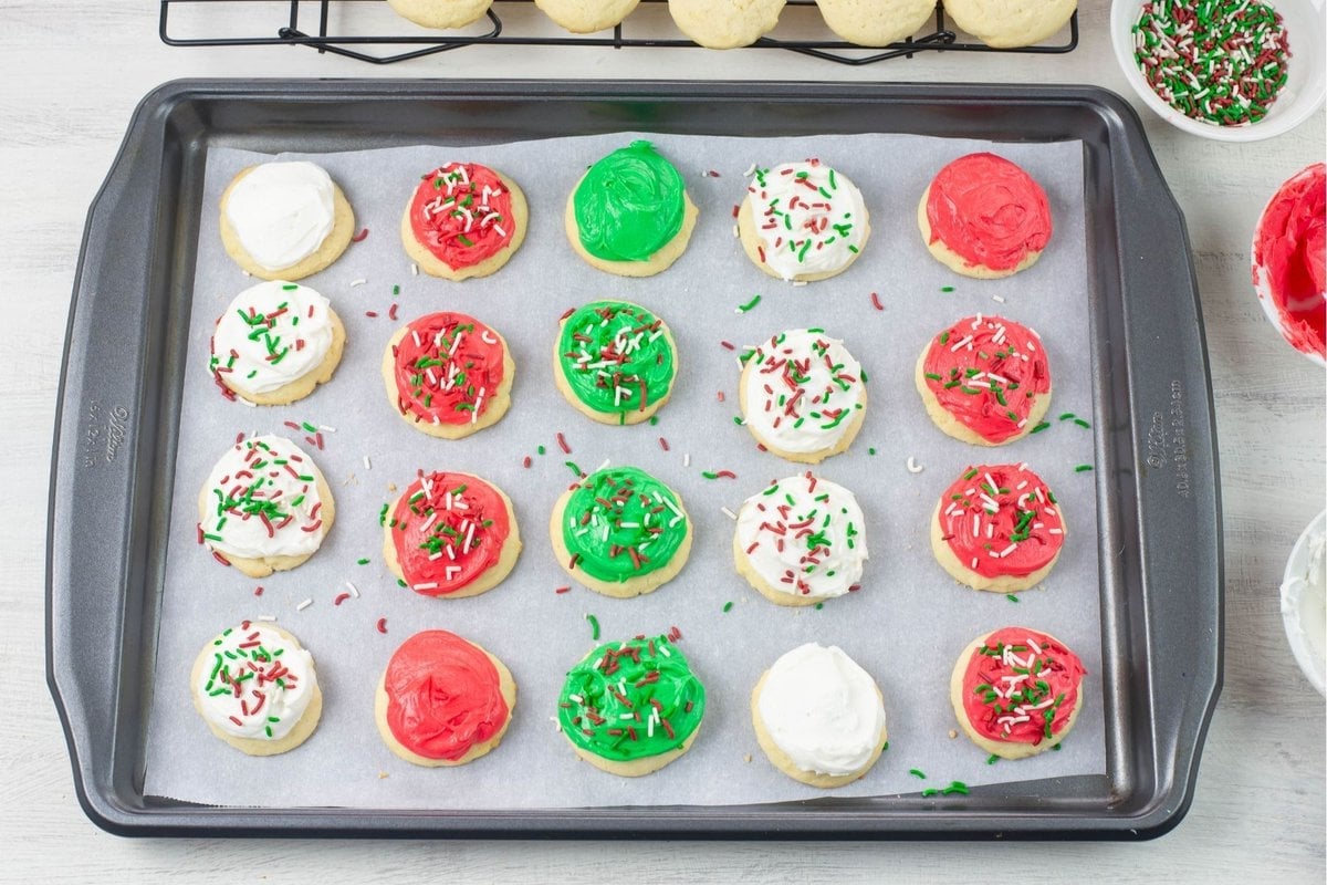 A large cookie sheet with an assortment of frosted and decorated Christmas cookies arranged in rows.
