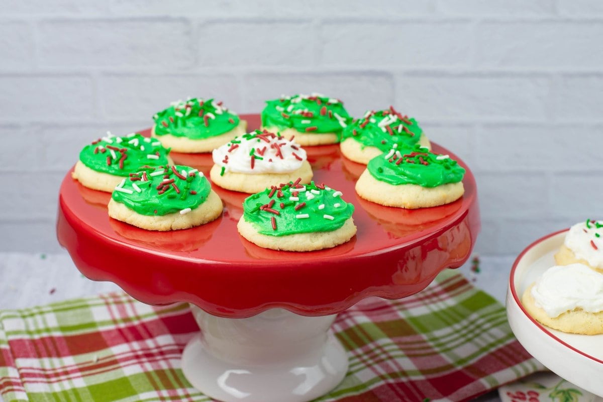 Green frosted Christmas cookies on a red cake stand.