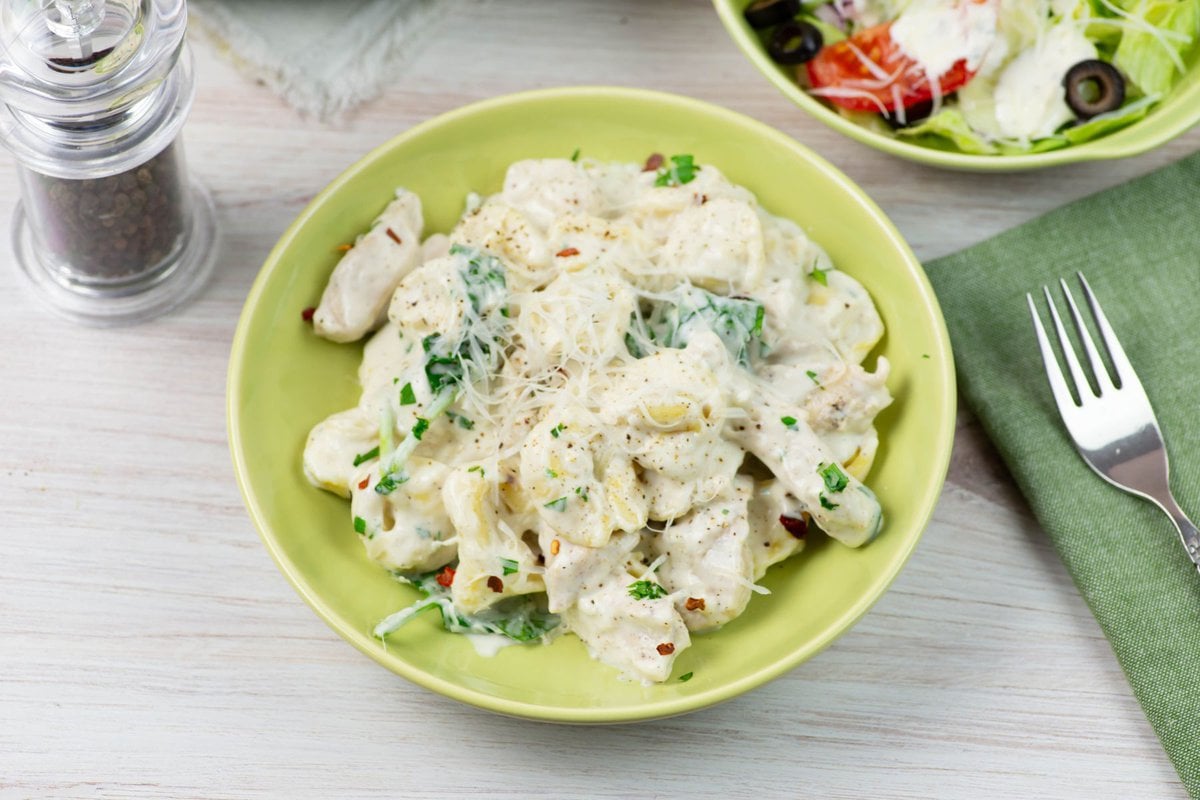 A serving of chicken tortellini alfredo served with a salad.