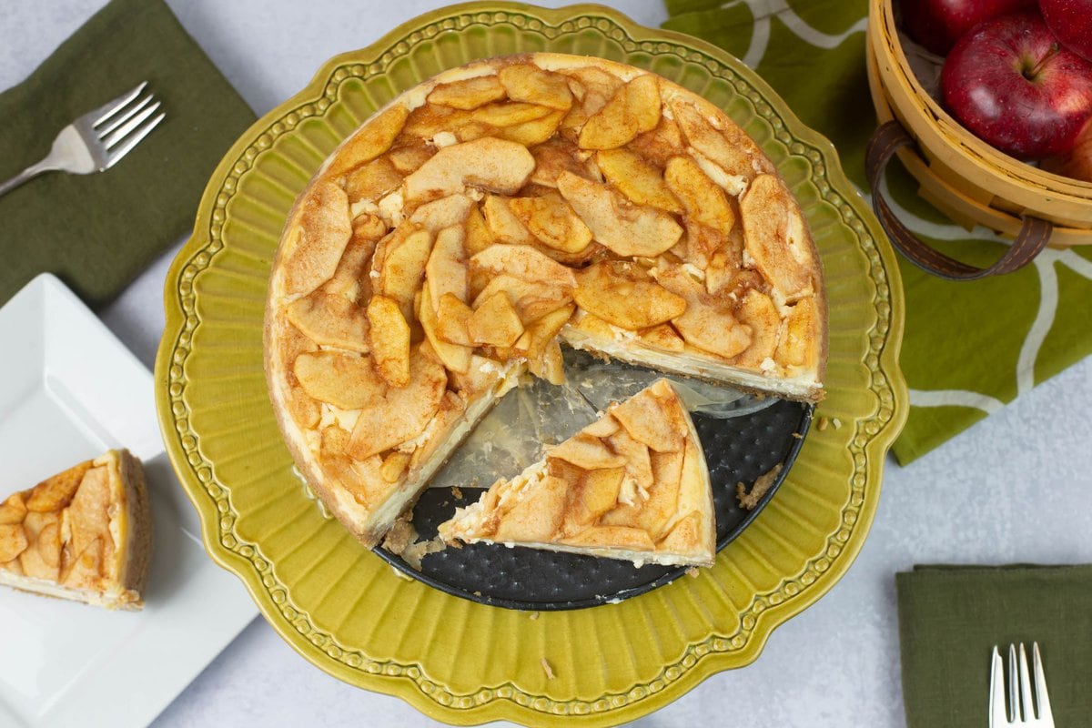 Overhead image of an apple cheesecake with one slice cut out.