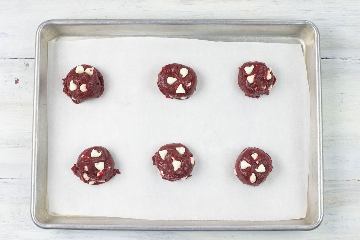 Scooped red velvet cake mix cookie dough on a baking sheet.