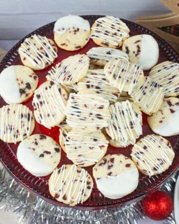 White Chocolate drizzled cranberry cookies on a red glass cake stand.