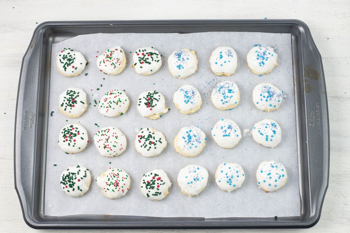 Frosted Italian Christmas cookies on a baking sheet.