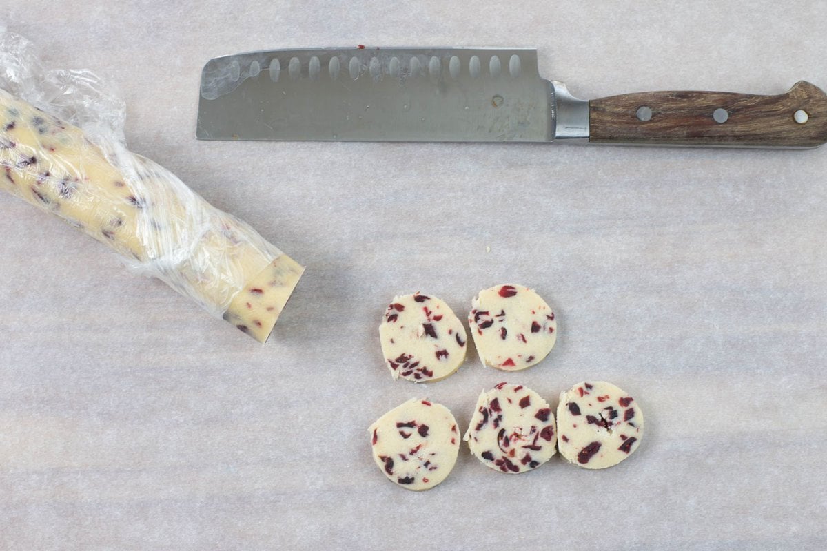 Sliced cranberry cookies on a cutting board.