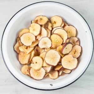 Dehydrated Apple Slices in a large bowl with step by step directions how to make.