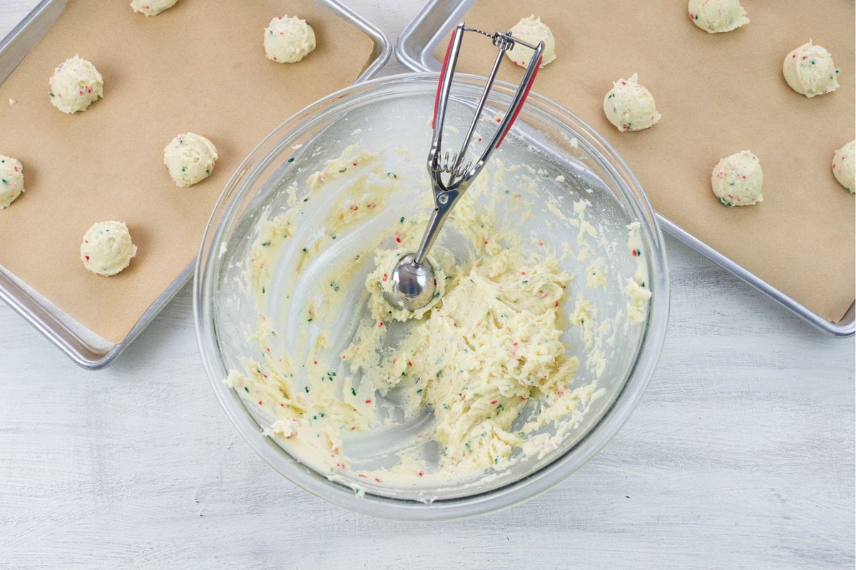Scooping funfetti cookie dough and placing the dough balls on a cookie sheet.