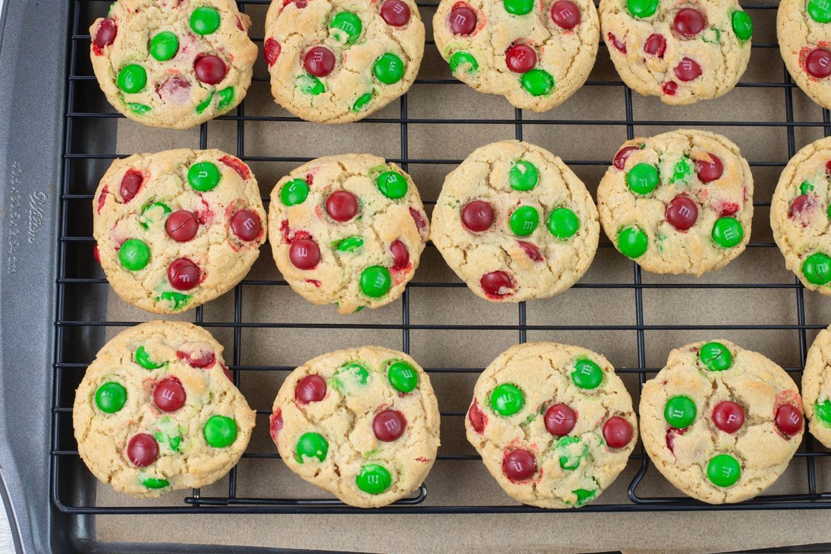 Red and green M&M cookies on a wire rack.