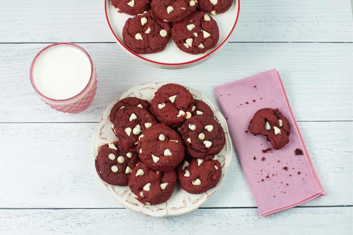 Red Velvet cake mix cookies piled on a serving plate with a glass of milk.