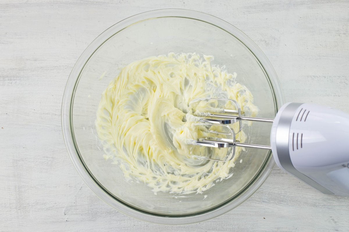 A glass mixing bowl with creamed softened butter in it.