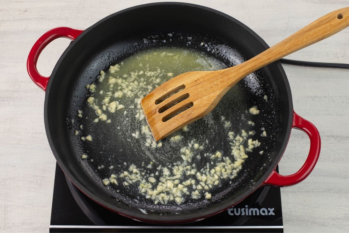 A skillet with melted butter and minced garlic.