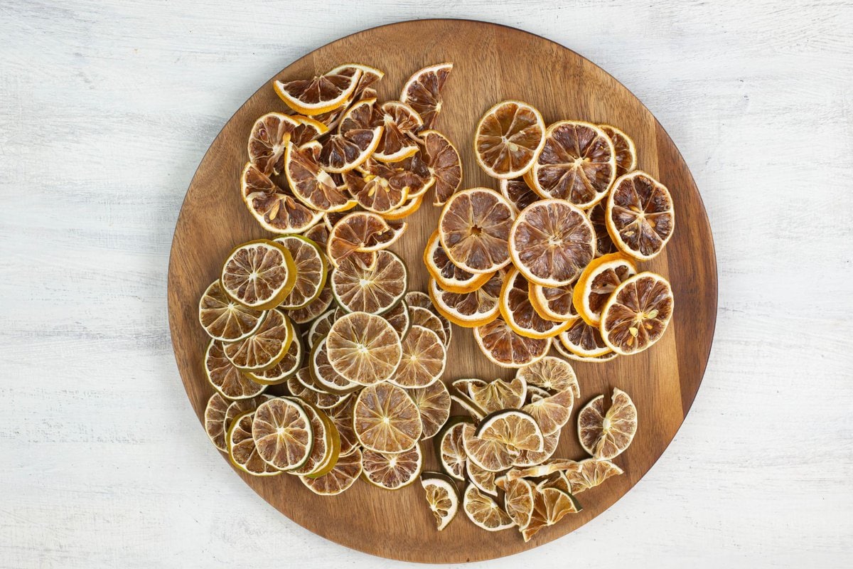 Dehydrated lime and lemon slices piled on a wooden plate.