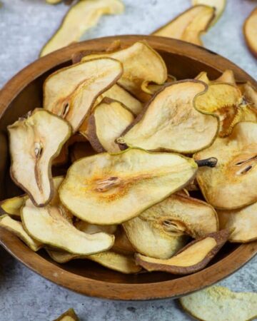 Dehydrated pear slices in a wooden bowl.
