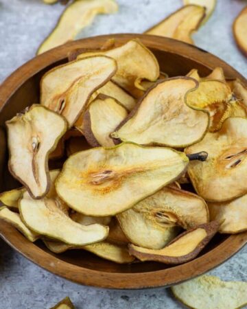 Dehydrated pear slices in a wooden bowl.