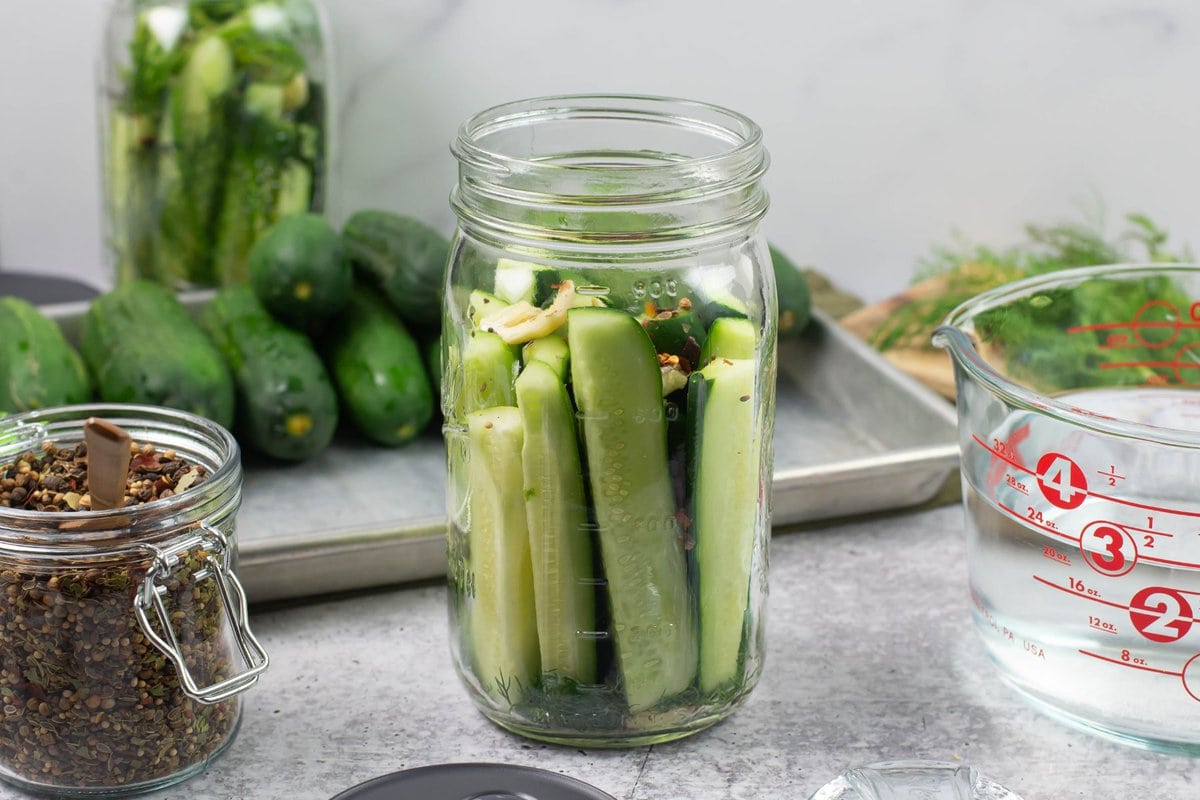 Packing cucumber wedges into a quart mason jar.