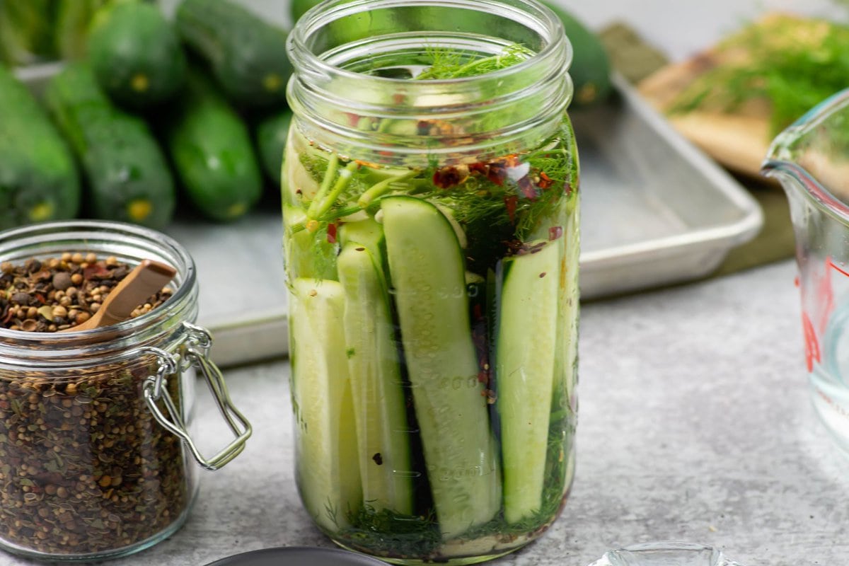 A quart jar filled with cucumber wedges and filled with pickling brine.