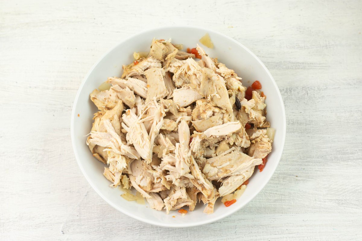 Shredded slow cooked chicken thigh pieces in a bowl.