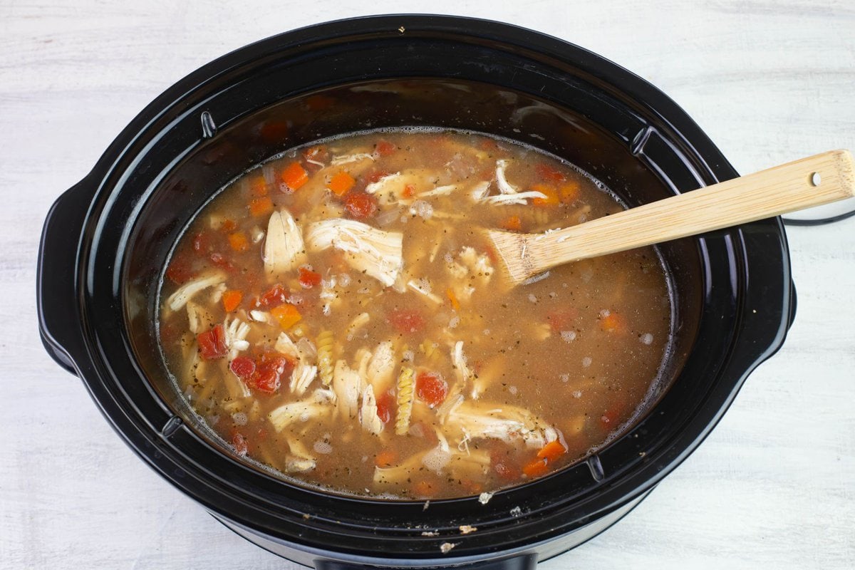 The cooked chicken and uncooked noodles added to the soup.