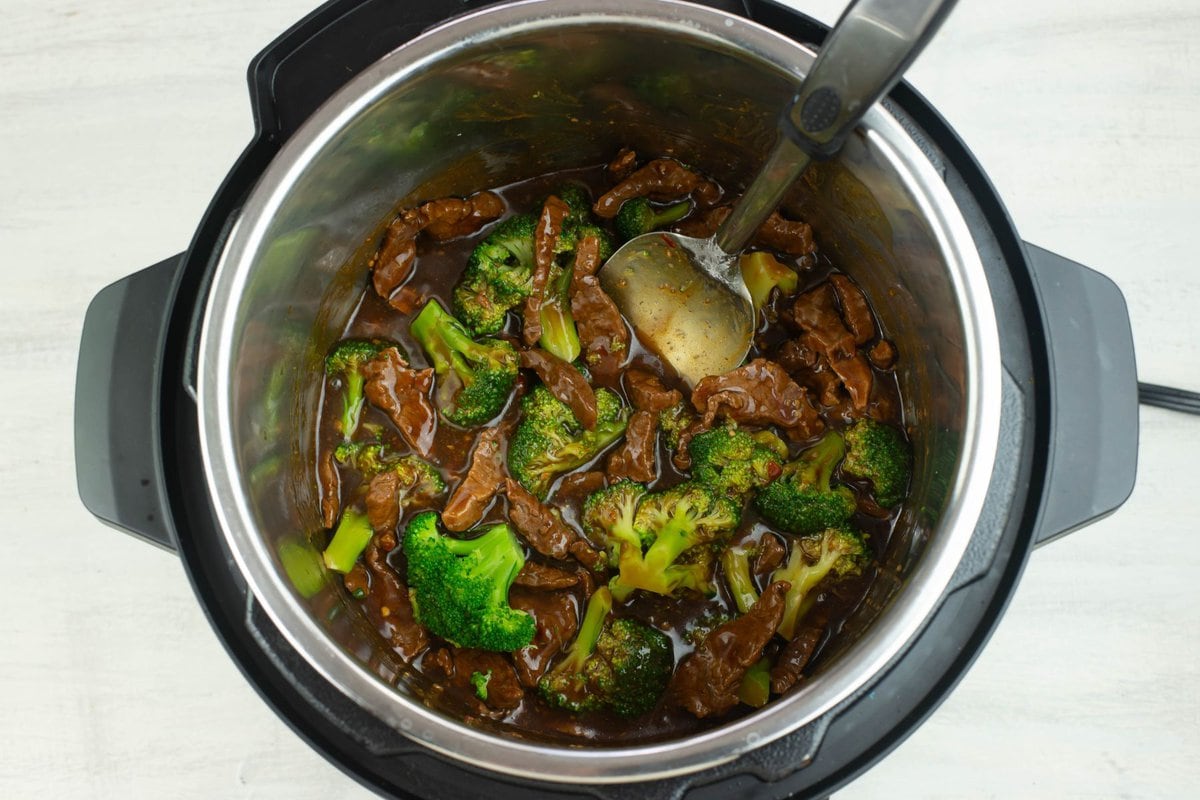 Adding broccoli to the beef and sauce.