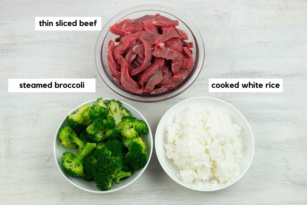 Thinly sliced beef, fresh broccoli and cooked white rice in medium bowls.