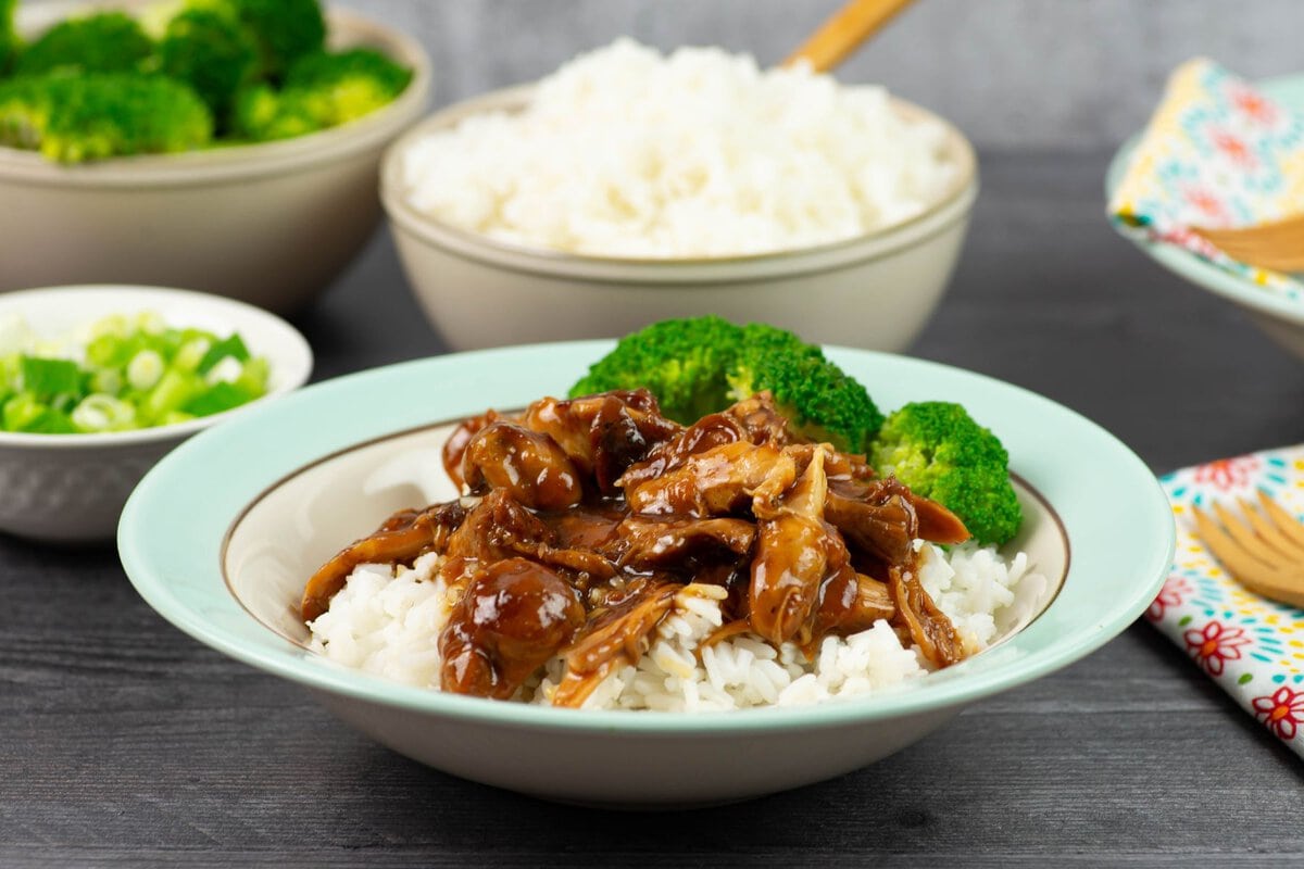 Chicken Adobo served over white rice and served in a bowl.