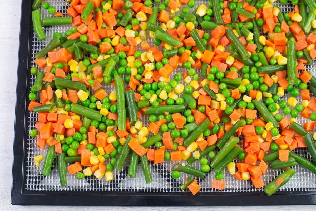 The thawed vegetables spread out on a square dehydrator tray.
