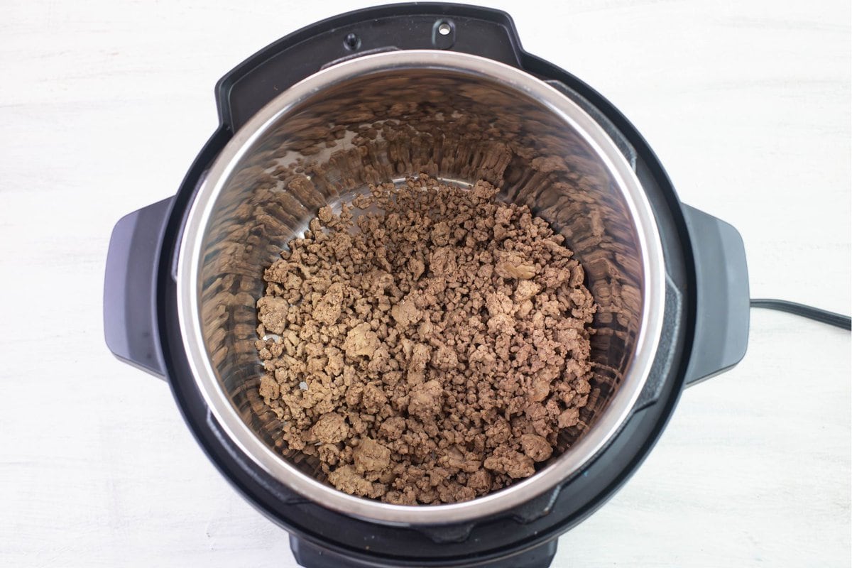Browned ground beef in the Instant Pot inner pot.