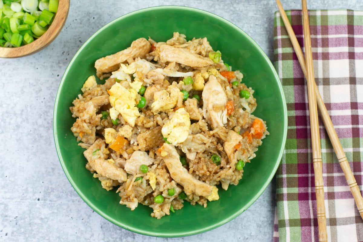 The finished chicken fried rice in a green bowl with chop sticks.