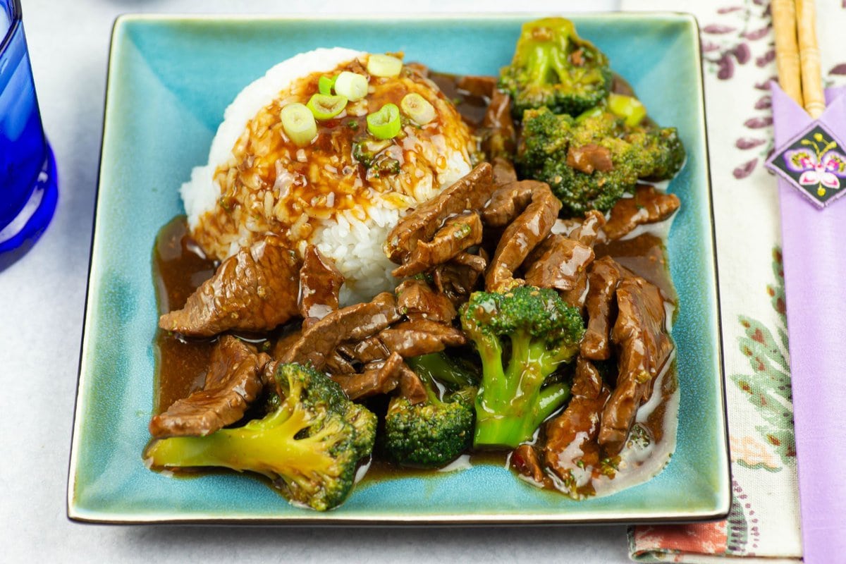 Beef broccoli with rice on a square dinner plate.