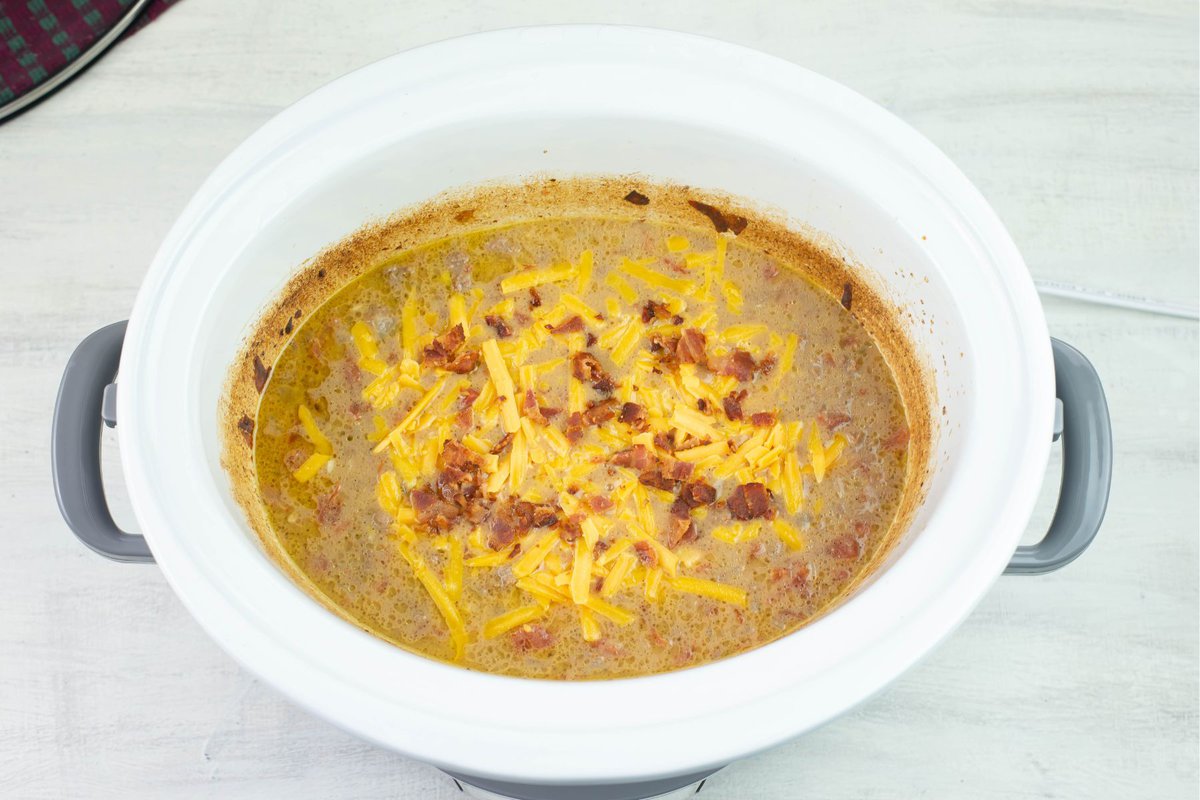 Topping cheeseburger soup with shredded cheese and bacon.