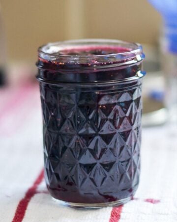 A jelly jar filled with blueberry jam.